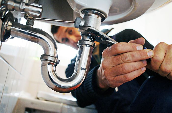 Close-up of plumber repairing sink with tool in bathroom